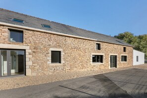 A stone building with multiple windows and a sloped roof.