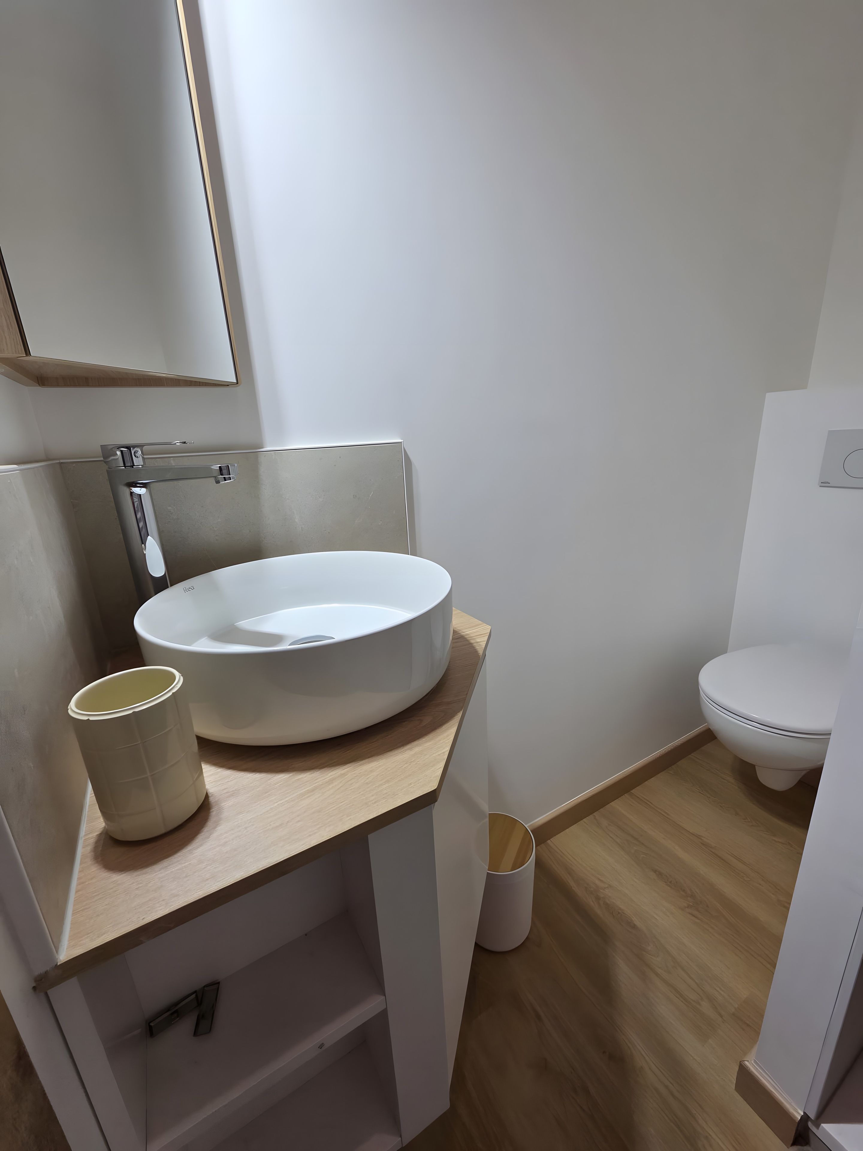 Un baño moderno con un lavabo redondo, un inodoro y un espejo.