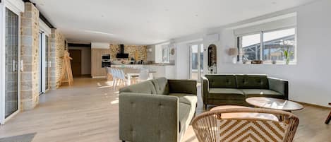 Ein geräumiger Wohnbereich mit einer modernen Küche, einem Essbereich und einer Sitzecke mit Sofas und Sesseln.