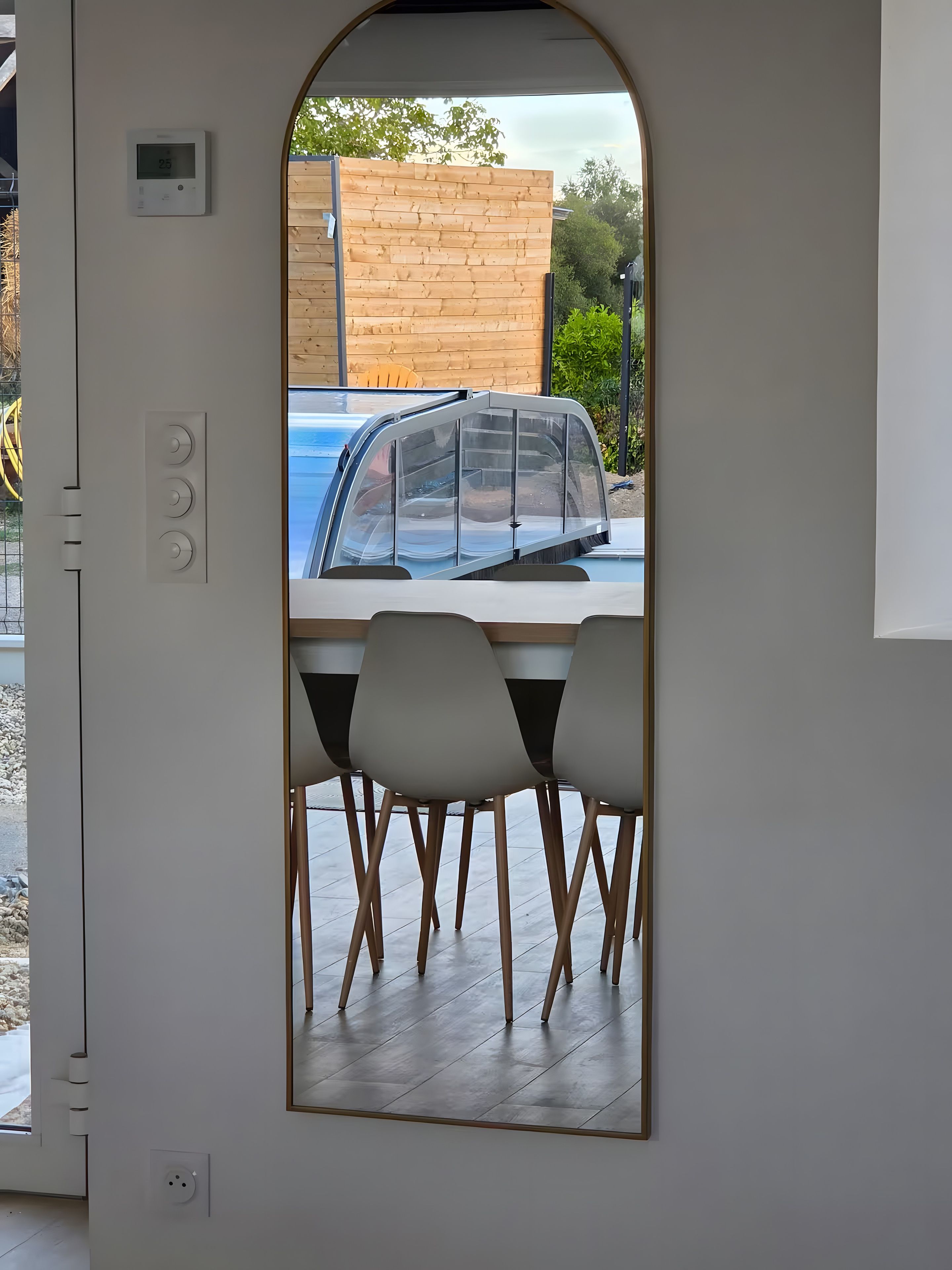 A modern interior with a dining area, a wooden wall, and a view of a blue car outside.