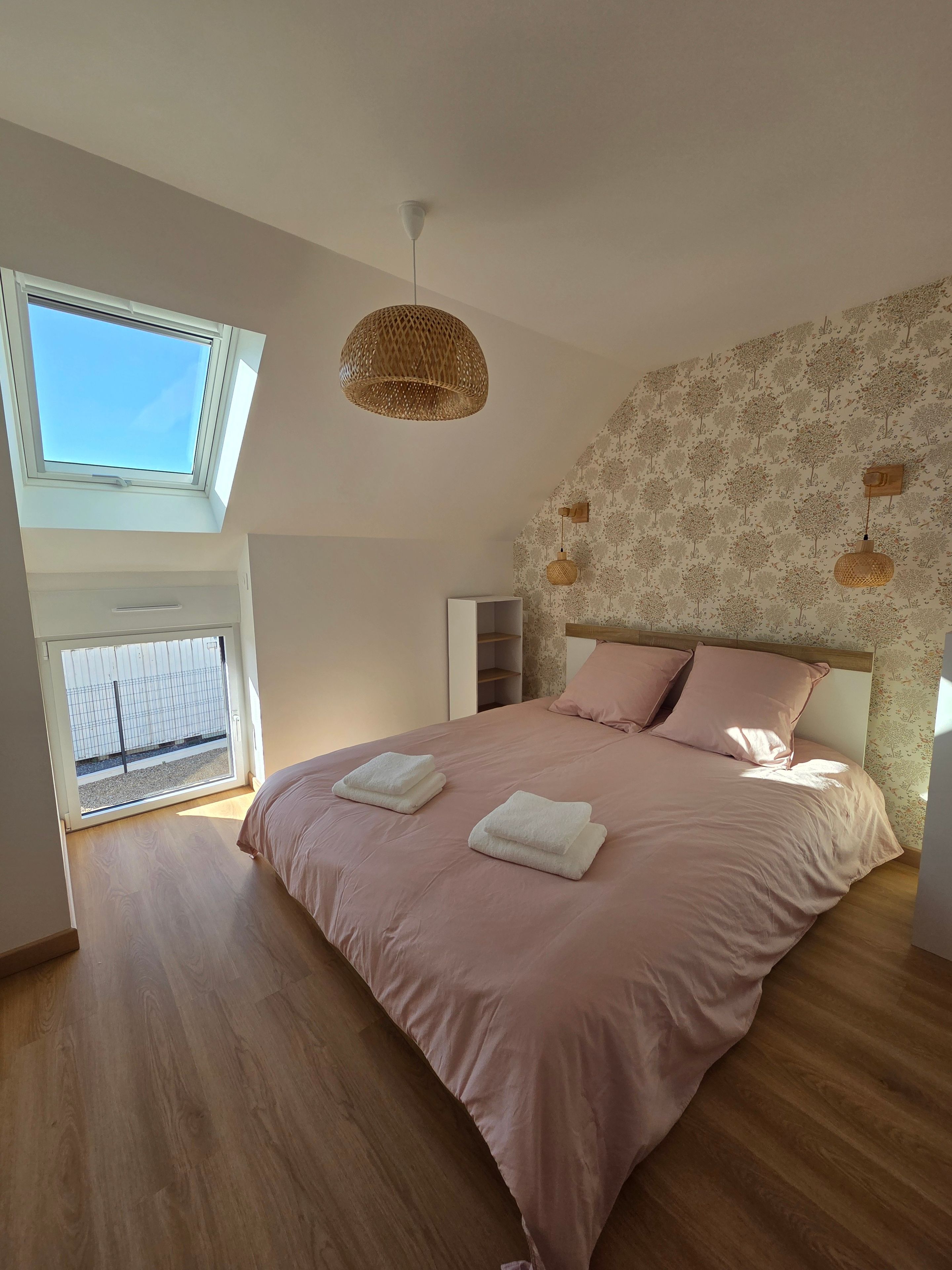 A bedroom with a large bed, a skylight, and a patterned wall.