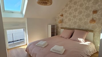A bedroom with a large bed, a skylight, and a patterned wall.