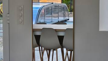 A modern interior with a dining area, a wooden wall, and a view of a blue car outside.