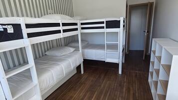 A bunk bed room with a wooden floor, a striped wall, and a hanging light fixture.