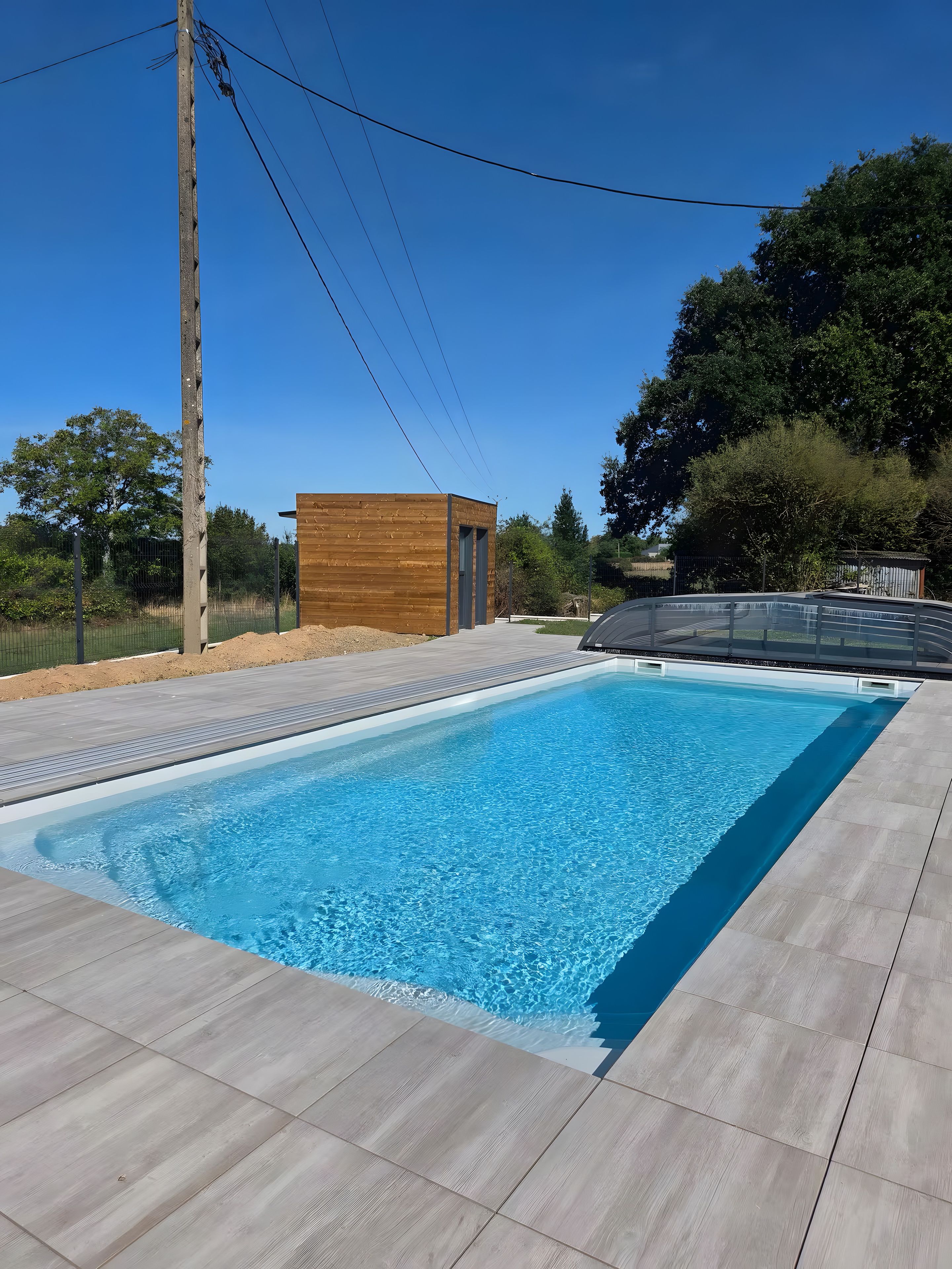A swimming pool with a wooden deck and a small wooden structure.