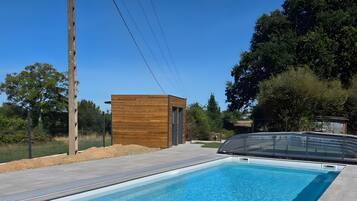 A swimming pool with a wooden deck and a small wooden structure.