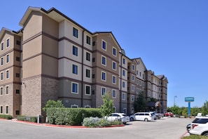 A multi-story hotel with a parking lot in front. - King Studio w/ Kitchen | Daily Breakfast + Pool (San Antonio)