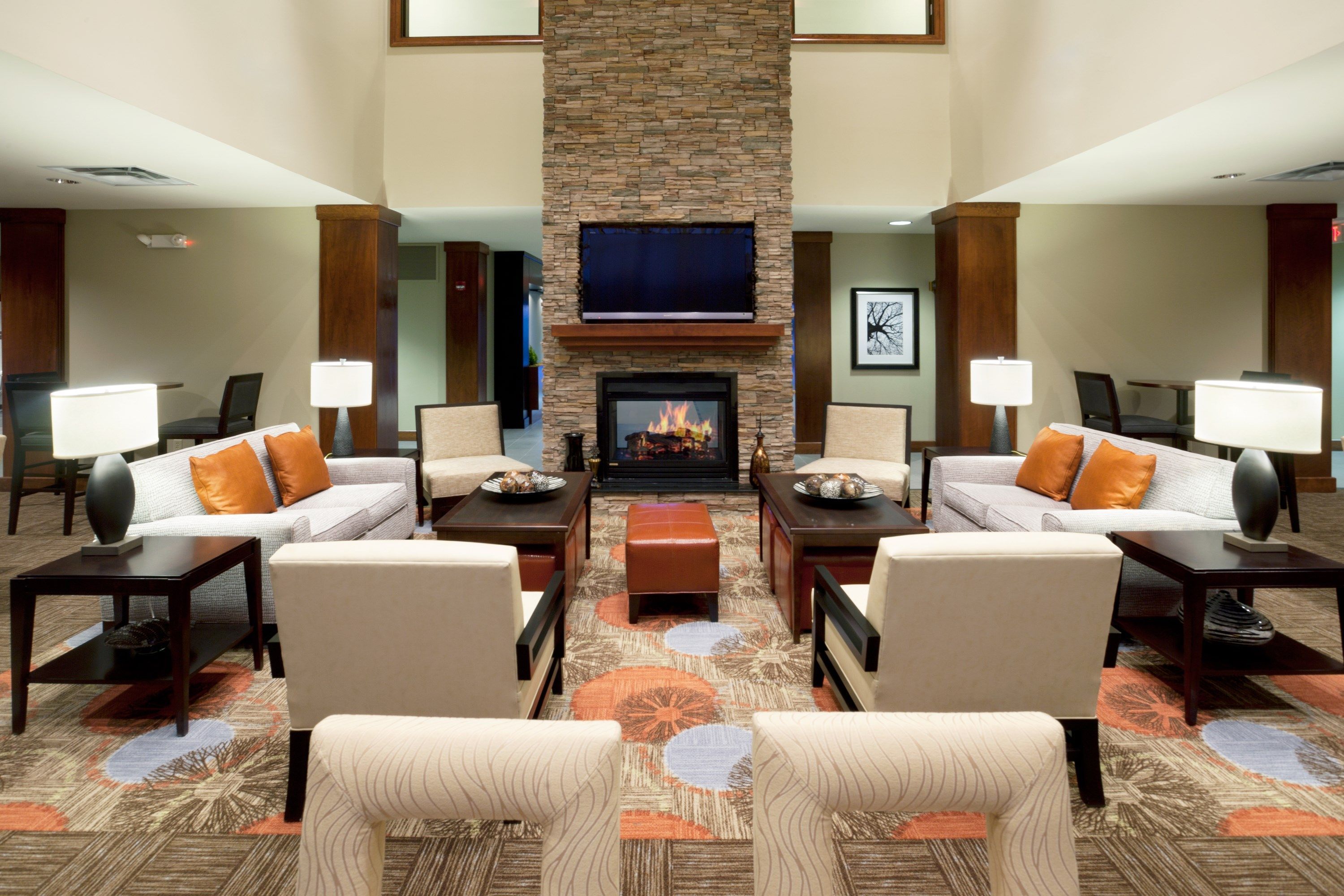 A hotel lobby with a fireplace, sofas, armchairs, and a patterned carpet.
