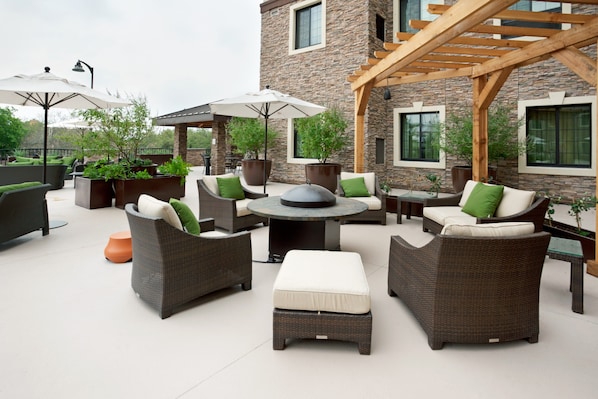 An outdoor patio area with wicker furniture, a round table, and potted plants.