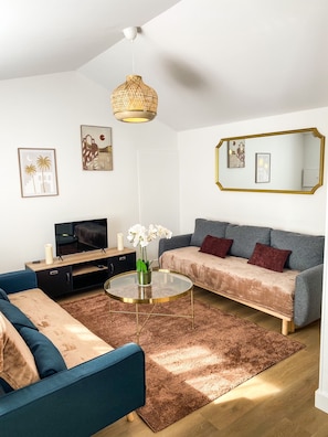 Un salon moderne avec un canapé, une table basse et un téléviseur.