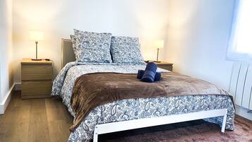 Quarto com cama, duas mesas de cabeceira e uma janela.