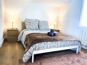 Une chambre à coucher avec un lit, deux tables de chevet et une fenêtre.