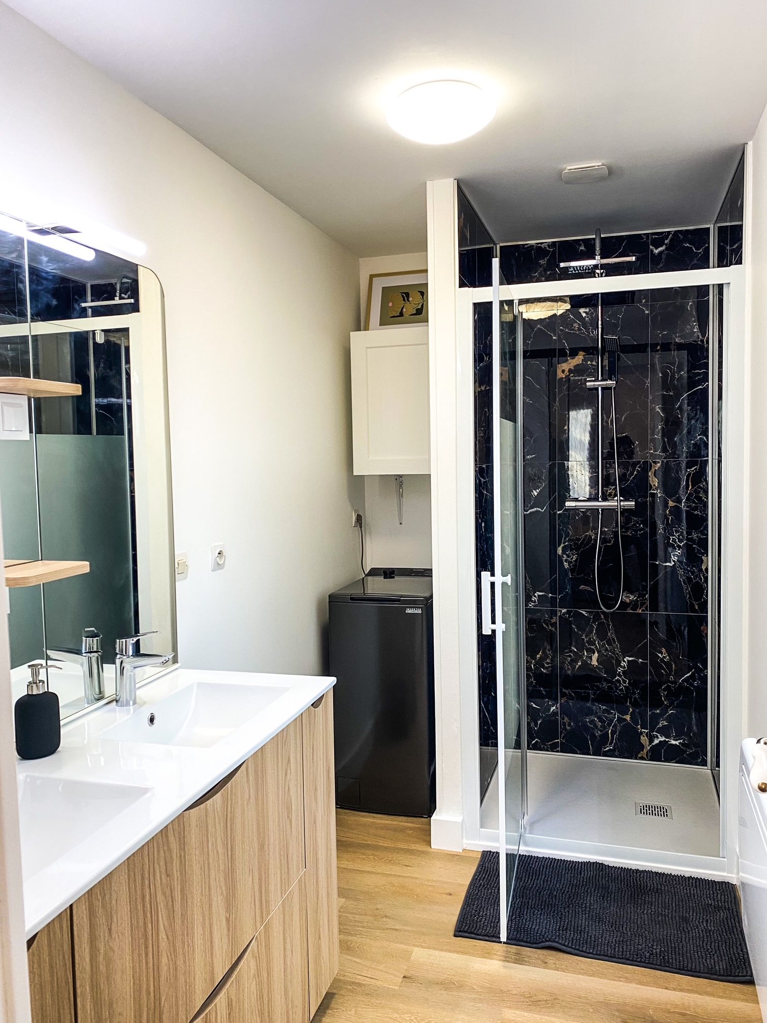 Une salle de bain moderne avec une douche à parois de verre, un lavabo blanc avec un meuble en bois et un miroir.