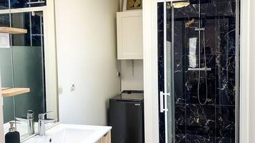 Une salle de bain moderne avec une douche à parois de verre, un lavabo blanc avec un meuble en bois et un miroir.