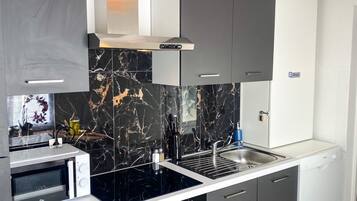 Cozinha moderna com forno embutido, micro-ondas e pia. Há um fogão com exaustor acima.