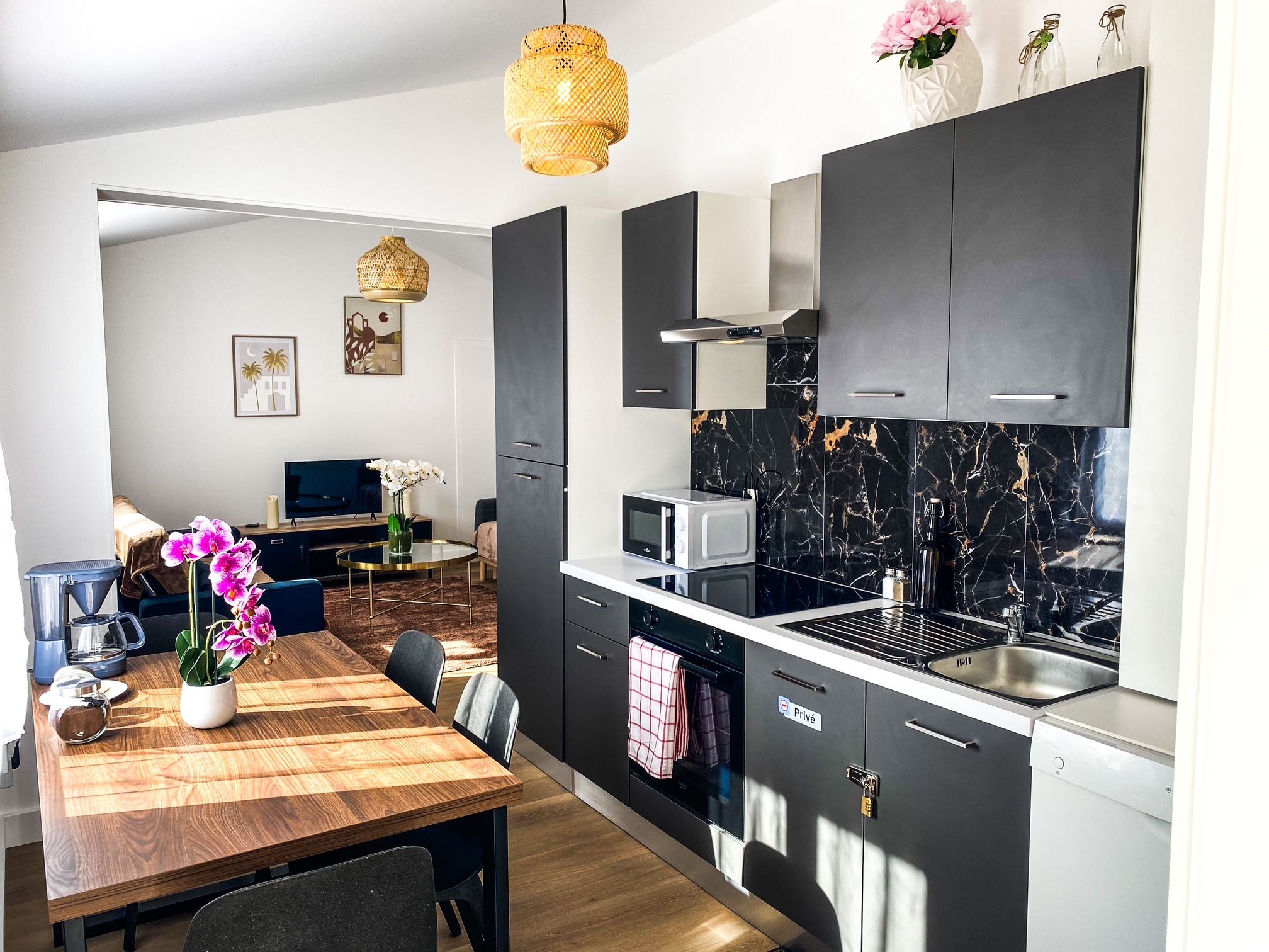 Une cuisine moderne avec des meubles de couleur sombre, un pare-feu en marbre et un coin repas comprenant une table et des chaises en bois.