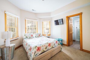 Ein Schlafzimmer mit einem Bett, einem Fernseher und einer Tür zu einem Badezimmer.