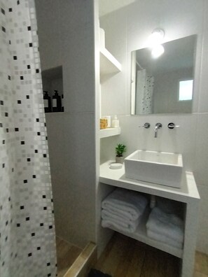 Un baño con lavamanos blanco, espejo y toallero.