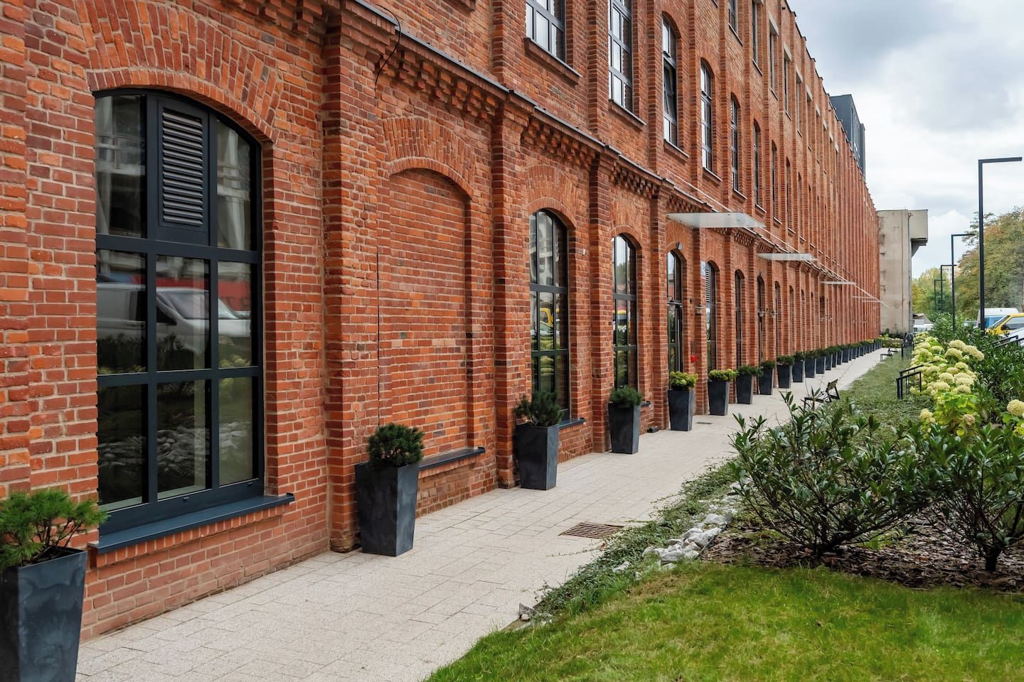 Een gebouw van rode baksteen met grote ramen en een geplaveid voetpad.