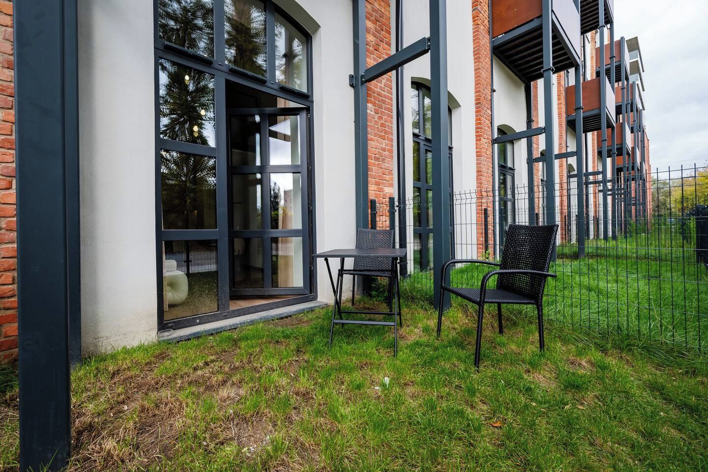 Un edificio moderno con ampie finestre e un'area verde con due sedie.