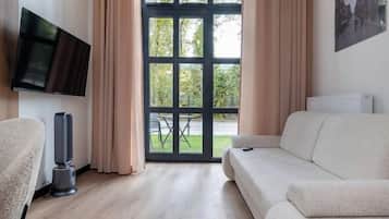 Een moderne woonkamer met een bank, een televisie en een groot raam met gordijnen.