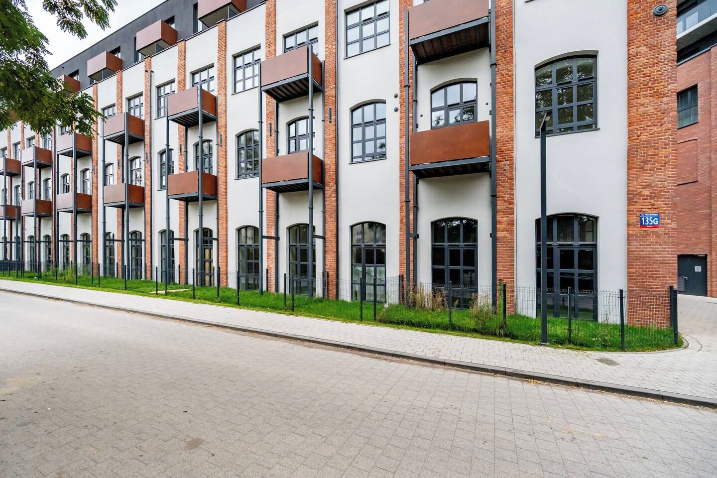Ein modernes, mehrstöckiges Gebäude mit Ziegelverkleidung, großen Fenstern und einem Flachdach.
