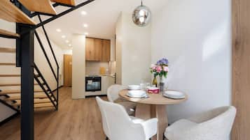 Een moderne keuken met houten kastjes, een inbouwoven en een eethoek met een ronde tafel en stoelen.