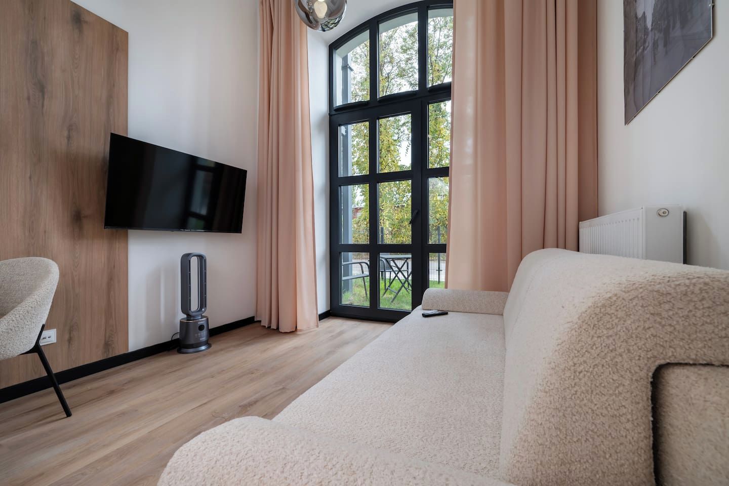 Un salon moderne doté d’un téléviseur à écran plat, d’une cheminée et d’une grande fenêtre avec des rideaux.