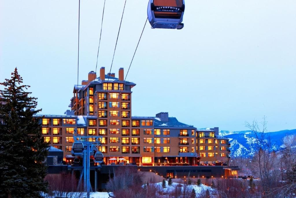 A multi-story hotel with a ski lift in the background.
