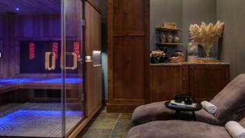 A room with a massage chair, a glass-enclosed sauna, and a wooden cabinet with decorative items.