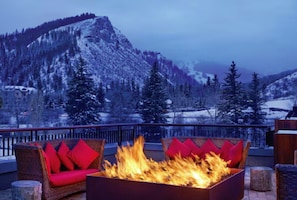 A balcony with a fire pit and red cushions, overlooking a snowy mountain landscape. - The Westin Riverfront Mountain Villages (Avon)