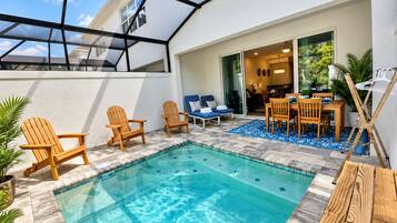 A swimming pool with lounge chairs and a dining area, surrounded by a covered patio.