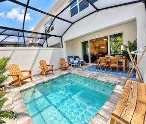 Piscina com espreguiçadeiras e área de refeições, cercada por um alpendre coberto.
