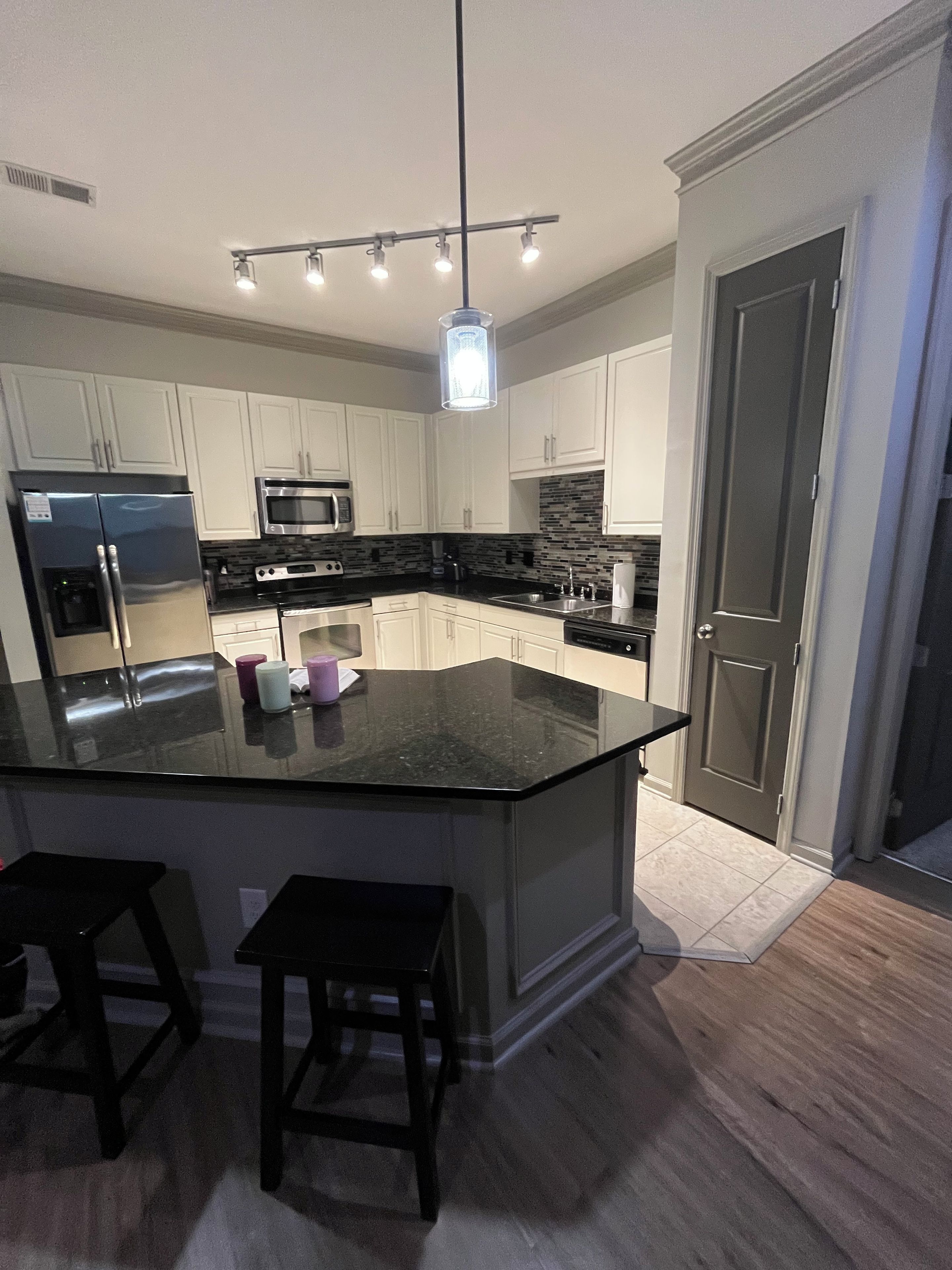 Cozinha moderna com ilha central, eletrodomésticos de aço inoxidável e luminária pendente.