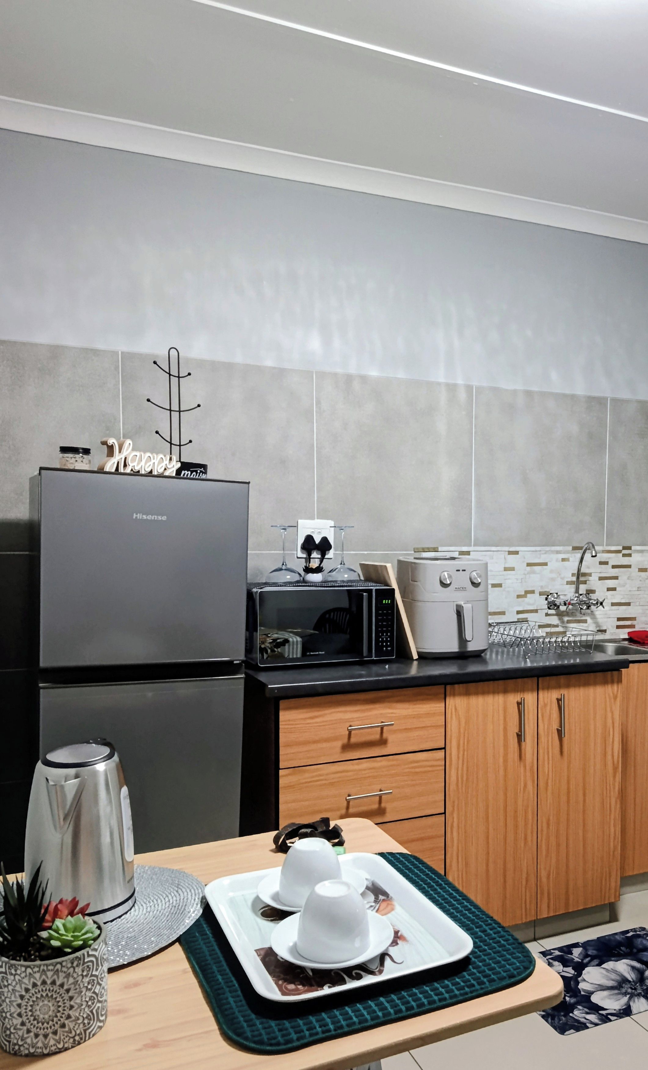 Una cocina moderna con un refrigerador Hisense, un microondas, un tostador y un lavamanos.