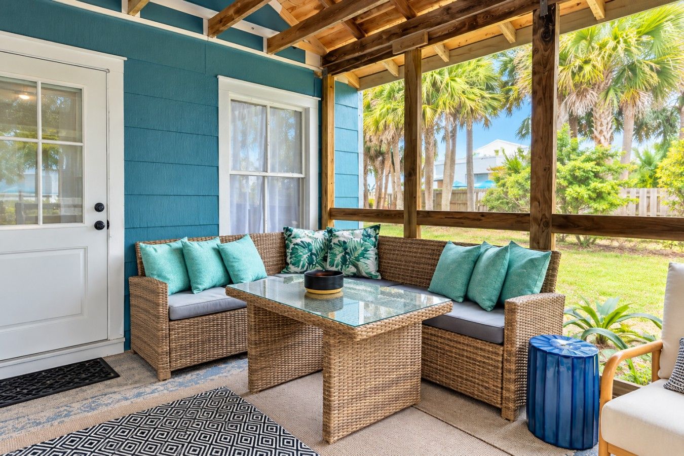 A covered porch with wicker furniture and a glass table.