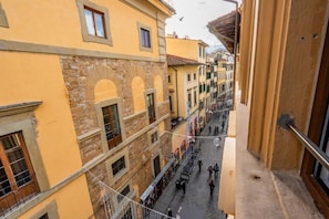 A narrow street with buildings on either side, featuring arched windows and a stone facade. - Lumi stays (Firenze)