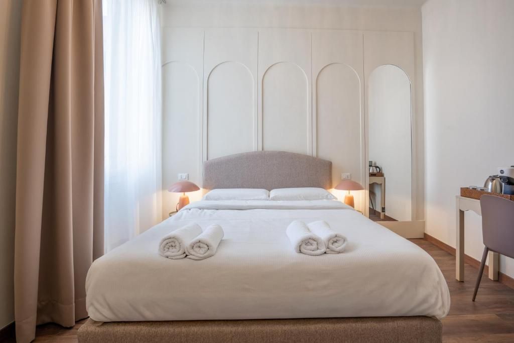 A hotel room with a large bed, two bedside lamps, a desk with a chair, and a mirror on the wall.