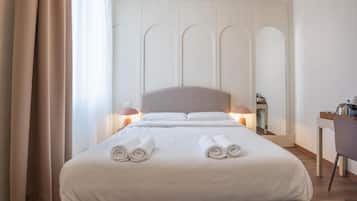 A hotel room with a large bed, two bedside lamps, a desk with a chair, and a mirror on the wall.