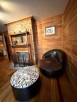 A cozy room with a fireplace, a leather armchair, and a zebra-patterned ottoman. - Historic Wiseman Retreat (Newland)