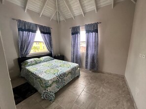 Ein Schlafzimmer mit Bett, Vorhängen, einem Nachttisch und einem Fenster.