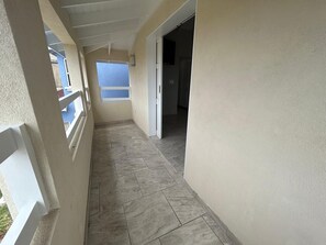 Ein Korridor mit gefliestem Boden, weißen Geländern und einer Tür zu einem anderen Raum.