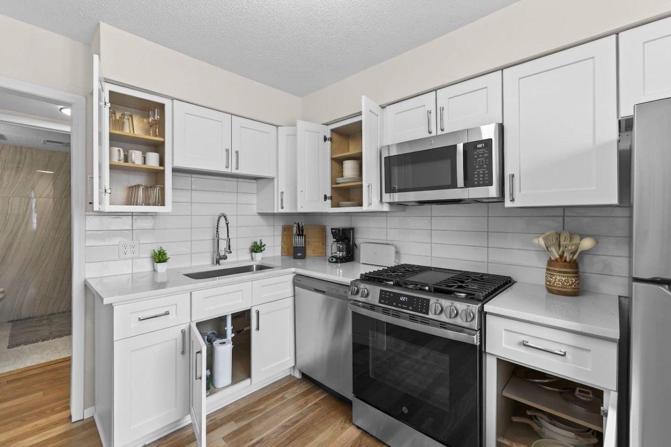 A modern kitchen with white cabinetry, a stainless steel stove, and a microwave.