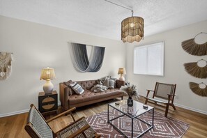A living room with a brown sofa, two side tables with lamps, a coffee table, and a patterned rug. - Designer Mid-Term Living Near Omaha Hospitals (Omaha)