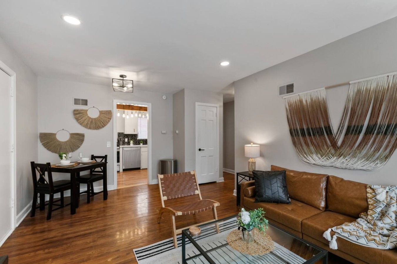 A modern living room with a sofa, coffee table, and a dining area with chairs and a table.