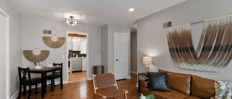 A modern living room with a sofa, coffee table, and a dining area with chairs and a table.