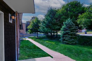 A residential property with a paved driveway leading to a front door, surrounded by a well-maintained lawn and mature trees. - Prime Location! HGTV Design! (Omaha)