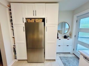 A compact kitchen with white cabinetry, a stainless steel refrigerator, and a window with frosted glass. - Sweet Beach House in the City! Great neighbourhood; family and pet friendly (Toronto)