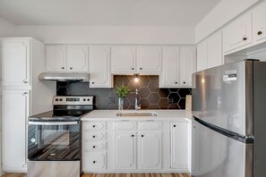 A modern kitchen with white cabinetry, a stainless steel refrigerator, a built-in oven, and a hexagonal backsplash. - Prime Location! HGTV Design!20#4 (Omaha)