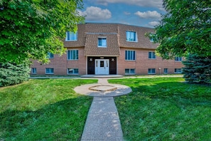 A multi-story brick building with a central entrance, surrounded by well-maintained grass and trees. - Prime Location! HGTV Design!20#4 (Omaha)